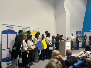 Des jeunes tenant le logo de Big Bloom cartonné sur une scène face à un public